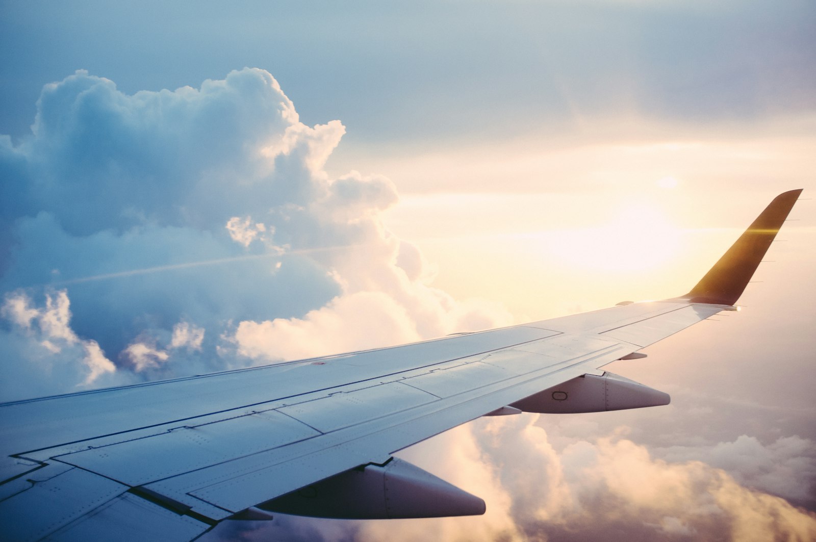 Asa de avião acima das nuvens ao pôr do sol
