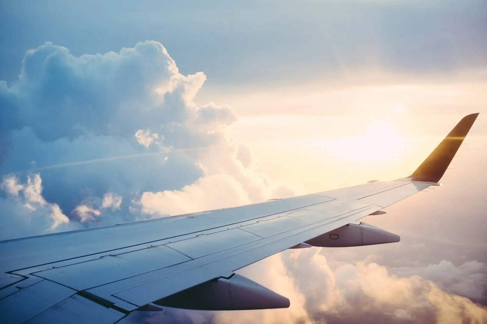 Asa de avião acima das nuvens ao pôr do sol